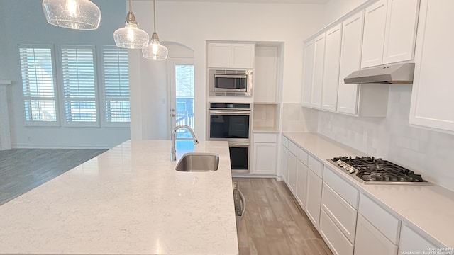 kitchen with white cabinets, stainless steel appliances, light hardwood / wood-style flooring, and hanging light fixtures