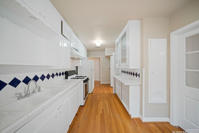 kitchen featuring white cabinetry, light wood-type flooring, white appliances, and tasteful backsplash