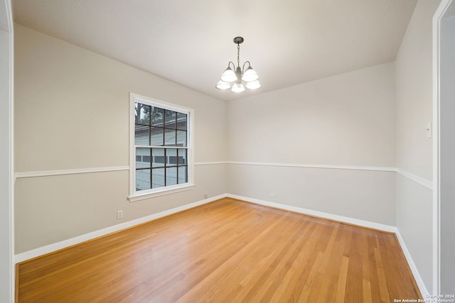 unfurnished room with hardwood / wood-style floors and a chandelier