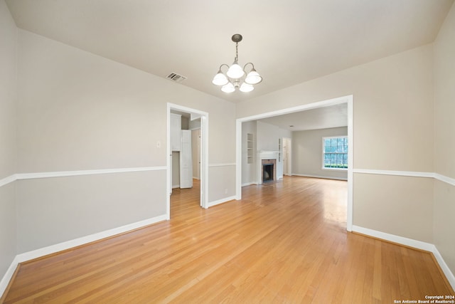 unfurnished dining area featuring light wood-type flooring and a notable chandelier