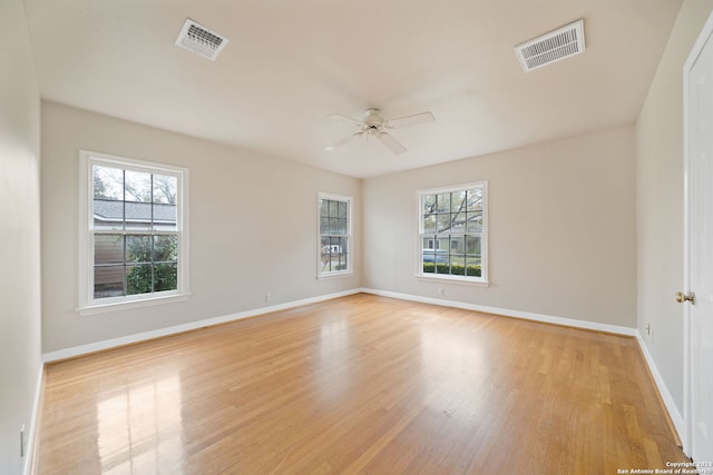 empty room with ceiling fan, a healthy amount of sunlight, and light hardwood / wood-style flooring