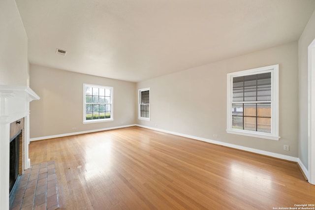 unfurnished living room with a brick fireplace and light wood-type flooring