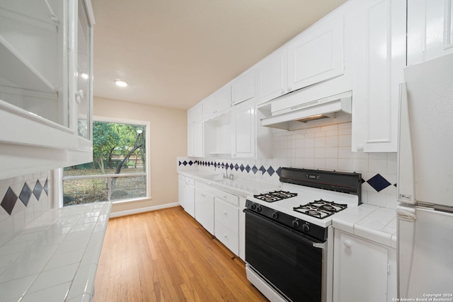 kitchen featuring decorative backsplash, light wood-type flooring, white appliances, tile countertops, and white cabinetry