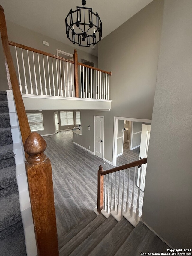 stairway with hardwood / wood-style floors, a high ceiling, and an inviting chandelier