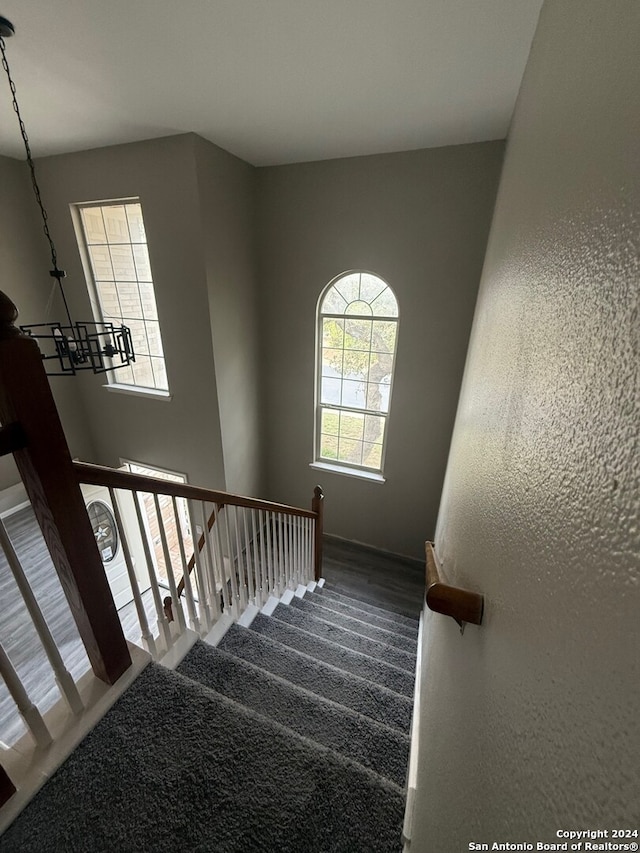 staircase with carpet and a notable chandelier