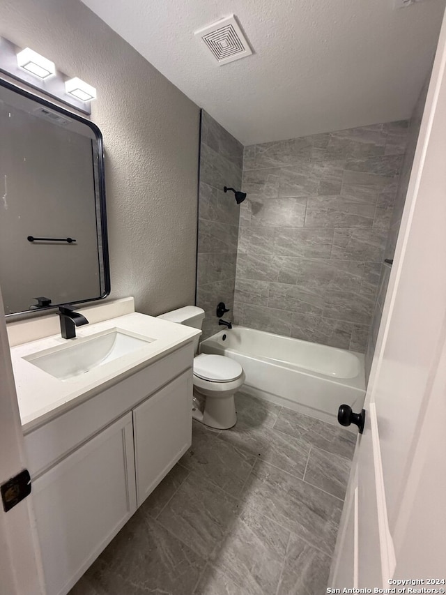 full bathroom featuring vanity, tiled shower / bath combo, a textured ceiling, and toilet