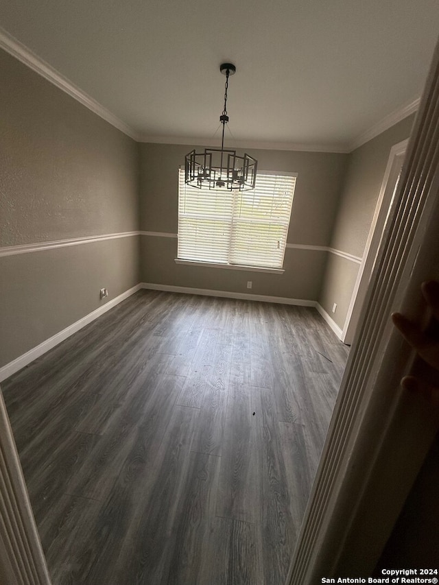 unfurnished dining area with crown molding, dark hardwood / wood-style flooring, and a notable chandelier