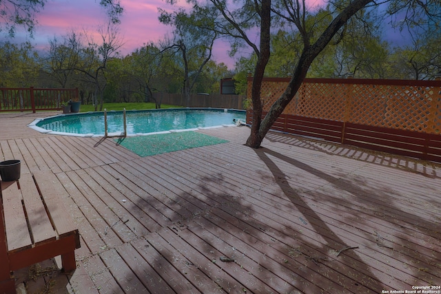 pool at dusk featuring a deck