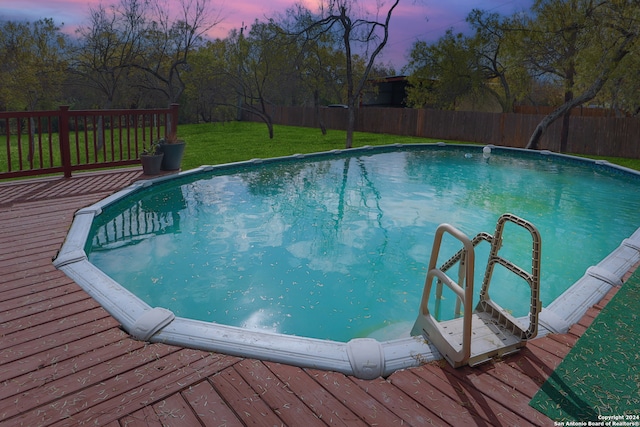 pool at dusk with a lawn and a wooden deck