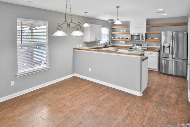 kitchen with white cabinets, a healthy amount of sunlight, stainless steel appliances, and pendant lighting