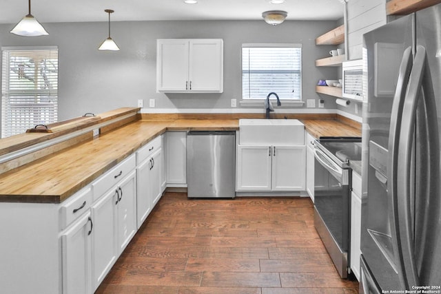 kitchen with stainless steel appliances, sink, pendant lighting, white cabinetry, and butcher block counters