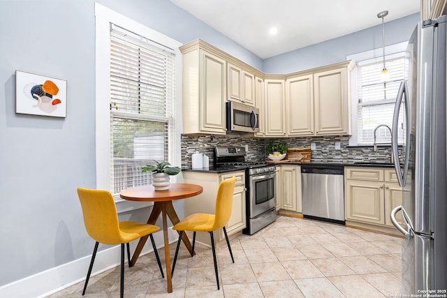 kitchen featuring stainless steel appliances, cream cabinetry, and dark countertops