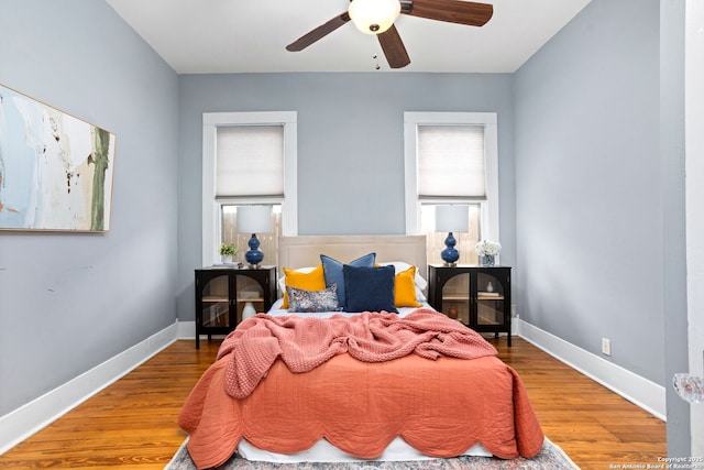 bedroom featuring a ceiling fan, baseboards, and wood finished floors