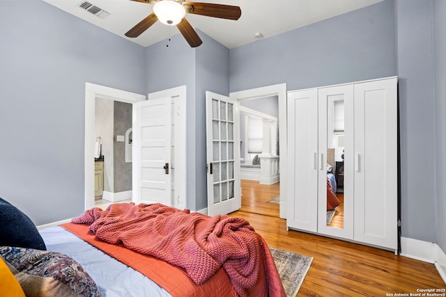 bedroom featuring light wood finished floors, baseboards, visible vents, connected bathroom, and a ceiling fan