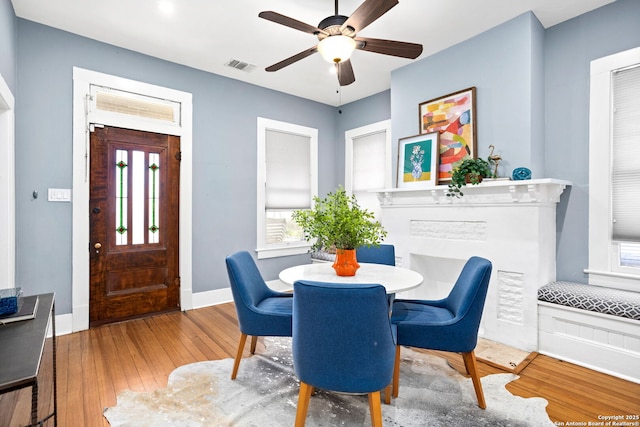 dining space with a ceiling fan, visible vents, baseboards, and hardwood / wood-style flooring