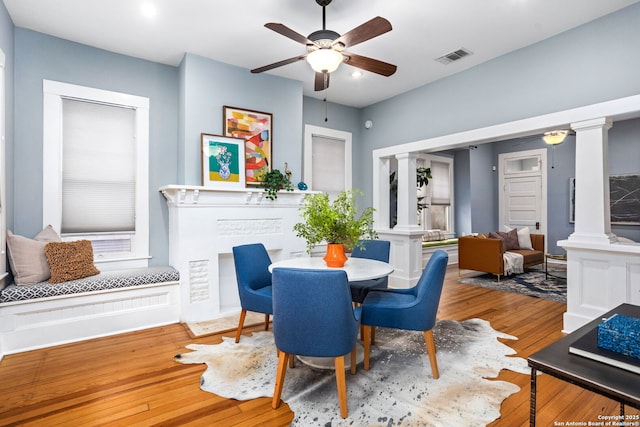 dining area with ornate columns, visible vents, a ceiling fan, and hardwood / wood-style floors