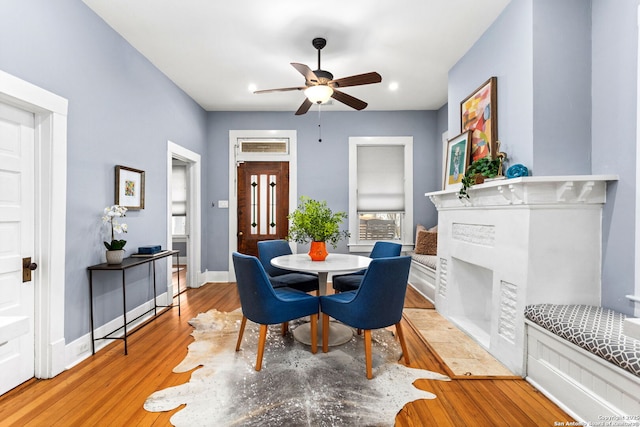 dining area with wood finished floors, a ceiling fan, and baseboards