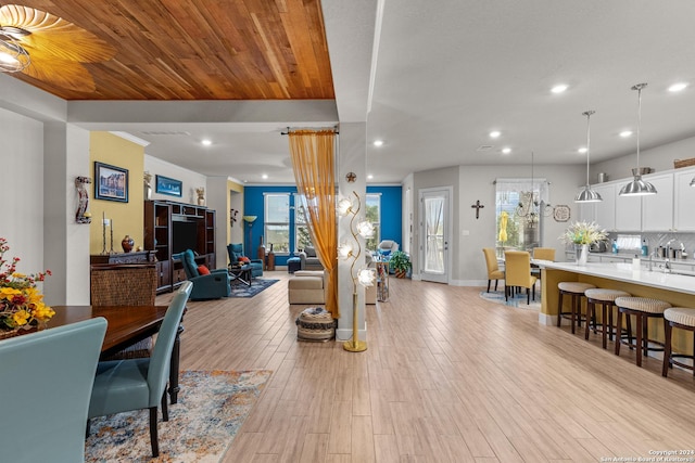 living room with light hardwood / wood-style floors, wood ceiling, sink, and ceiling fan