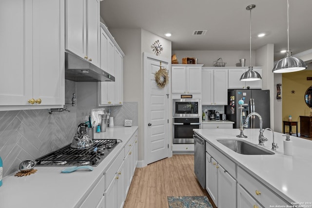 kitchen with decorative light fixtures, decorative backsplash, white cabinets, appliances with stainless steel finishes, and sink