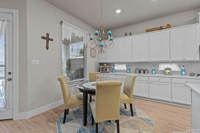 dining space with light hardwood / wood-style floors and a notable chandelier