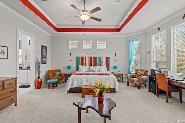 bedroom with ceiling fan, ensuite bath, light carpet, and a raised ceiling