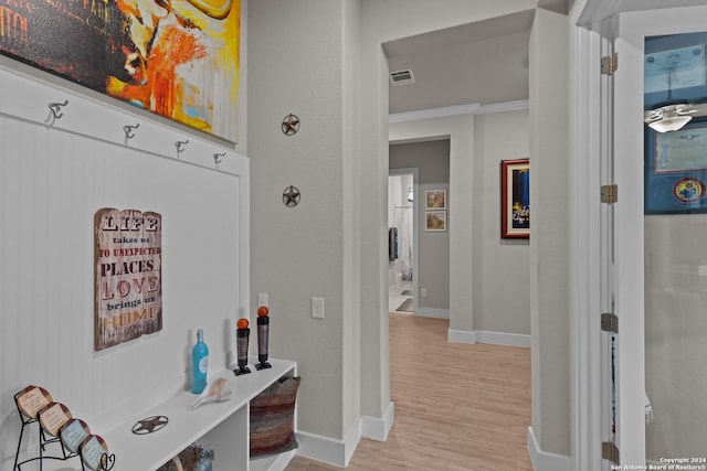 hallway with ornamental molding and light wood-type flooring