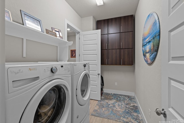 washroom featuring washer and dryer, cabinets, a textured ceiling, and light hardwood / wood-style flooring