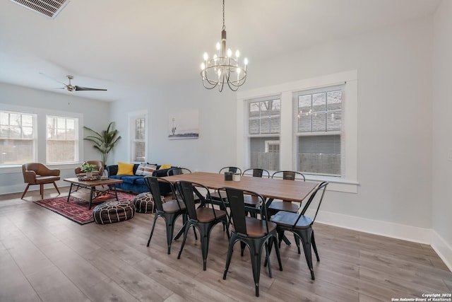 dining space featuring ceiling fan with notable chandelier and wood-type flooring