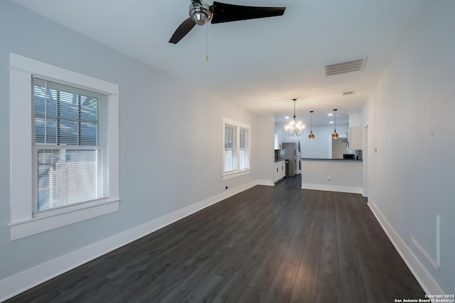 unfurnished living room with ceiling fan with notable chandelier and dark hardwood / wood-style floors