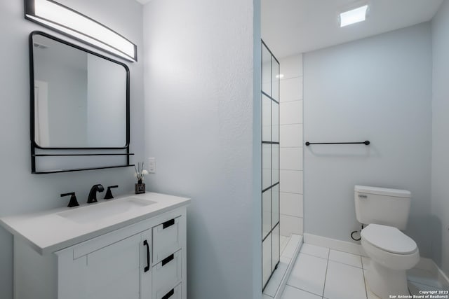 bathroom with tile patterned flooring, vanity, tiled shower, and toilet