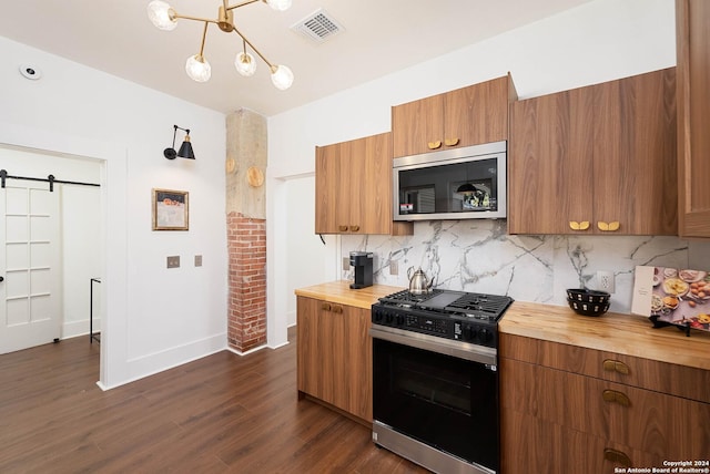 kitchen featuring wood counters, appliances with stainless steel finishes, a barn door, and tasteful backsplash