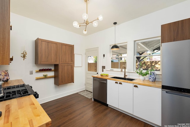 kitchen featuring refrigerator, stainless steel dishwasher, sink, decorative light fixtures, and white cabinetry