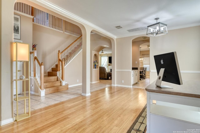 interior space featuring a notable chandelier, light wood-type flooring, and ornamental molding