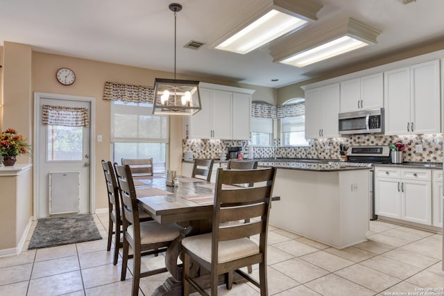 kitchen featuring white cabinetry, stainless steel appliances, hanging light fixtures, and backsplash