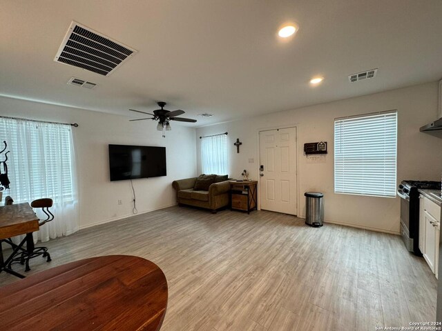 living room featuring ceiling fan, plenty of natural light, and light wood-type flooring