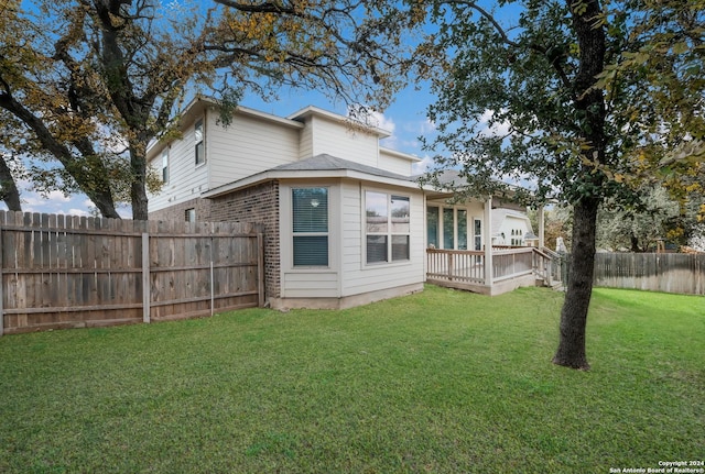 rear view of house featuring a lawn and a wooden deck