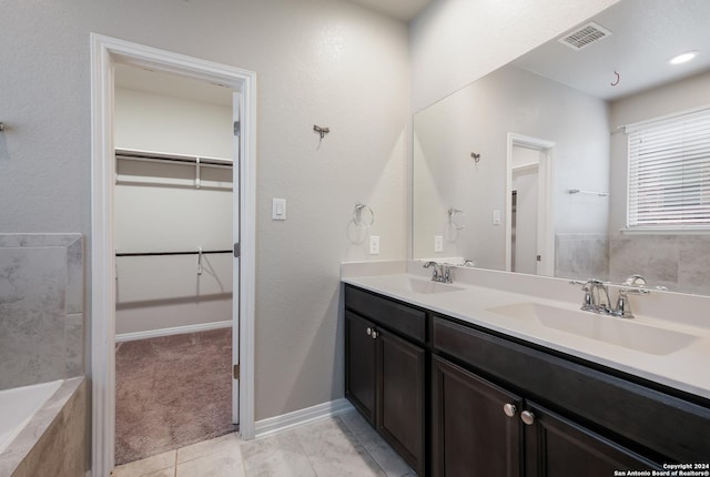 bathroom with vanity, tiled bath, and tile patterned floors