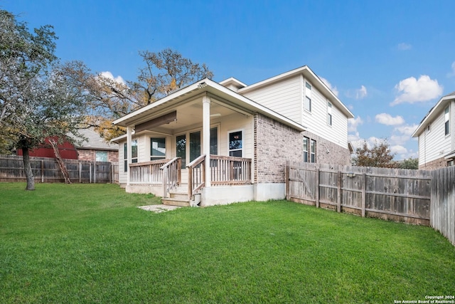 rear view of property featuring a lawn and covered porch