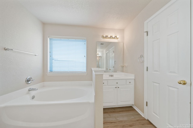 bathroom featuring vanity, a bath, a textured ceiling, and hardwood / wood-style flooring