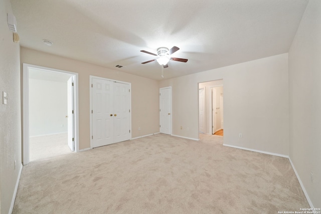 unfurnished bedroom with ceiling fan, ensuite bathroom, and light carpet