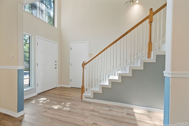 foyer entrance with plenty of natural light, a towering ceiling, and light wood-type flooring