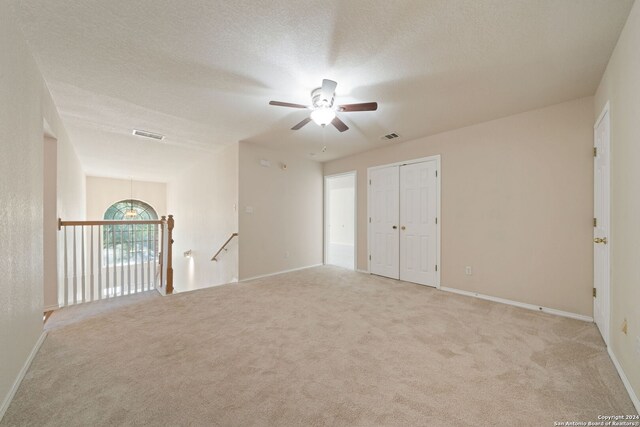 spare room featuring ceiling fan, light colored carpet, and a textured ceiling