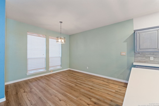 unfurnished dining area with a notable chandelier and light hardwood / wood-style floors