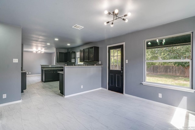 kitchen with kitchen peninsula, dark brown cabinets, an inviting chandelier, and plenty of natural light