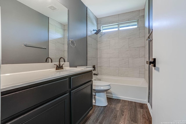 full bathroom featuring vanity, tiled shower / bath combo, hardwood / wood-style flooring, and toilet