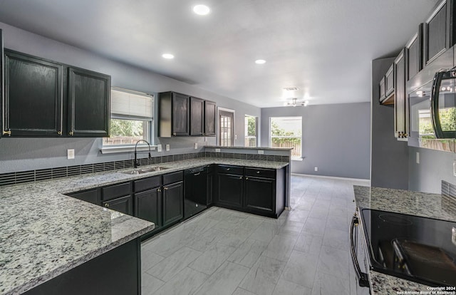 kitchen featuring dishwasher, range, sink, light stone countertops, and kitchen peninsula