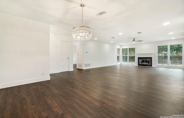 unfurnished living room featuring ceiling fan with notable chandelier and dark hardwood / wood-style flooring