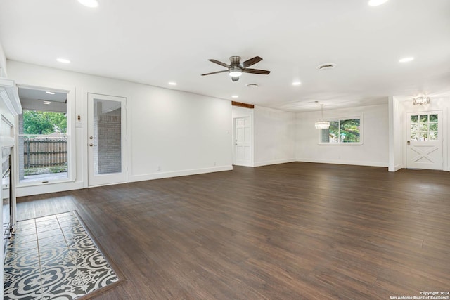 unfurnished living room with ceiling fan, dark wood-type flooring, and a healthy amount of sunlight