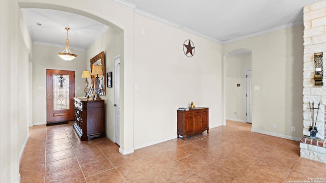 foyer entrance featuring a stone fireplace and crown molding