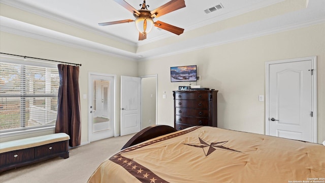 carpeted bedroom with a tray ceiling, ceiling fan, and ornamental molding